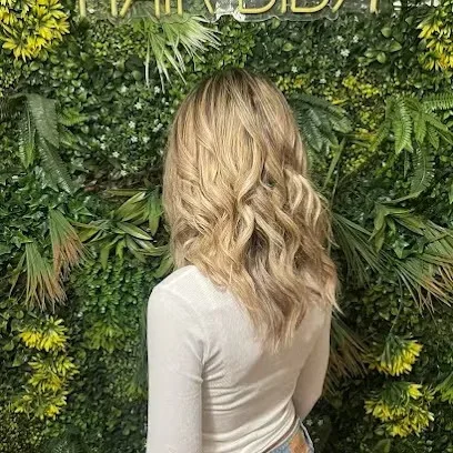Soft blonde waves photographed from behind in front of the HairBiba neon sign
